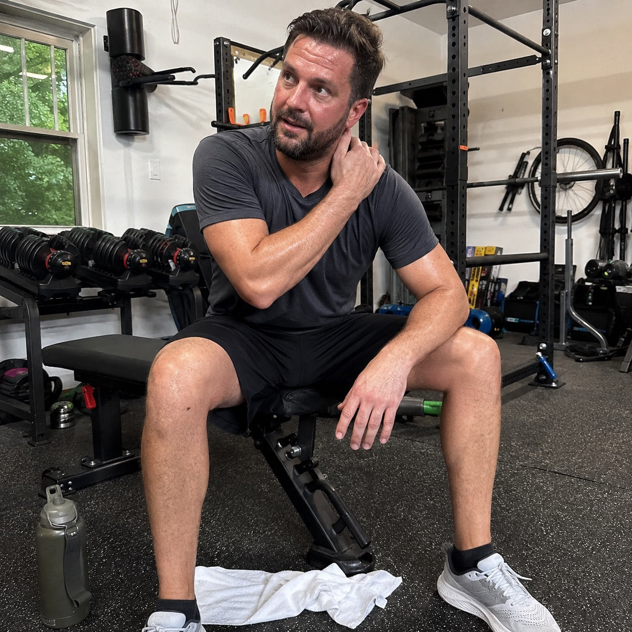 Active man resting on a bench in his home gym after strength training