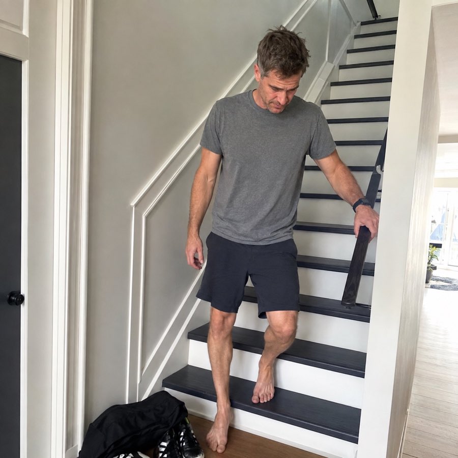 Adult recreational soccer player walking carefully down the stairs the morning after a match